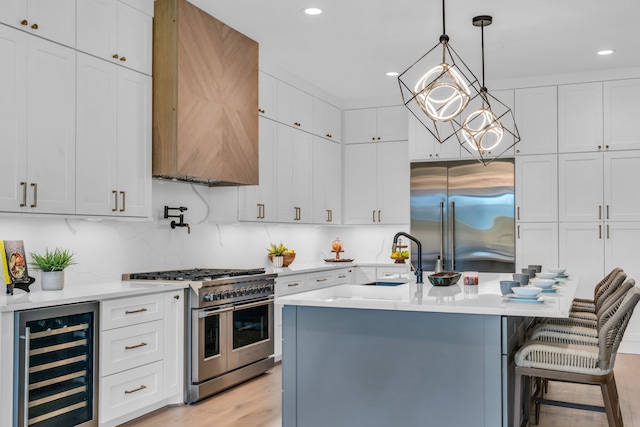 kitchen with premium appliances, beverage cooler, sink, light hardwood / wood-style flooring, and white cabinets