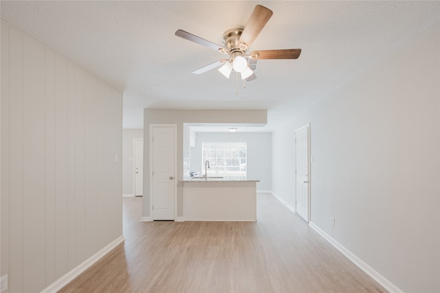 empty room with wood walls, light hardwood / wood-style floors, and ceiling fan