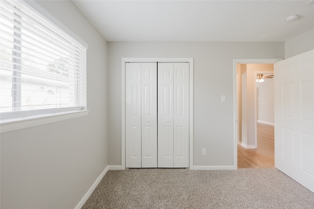 unfurnished bedroom with light carpet and a closet