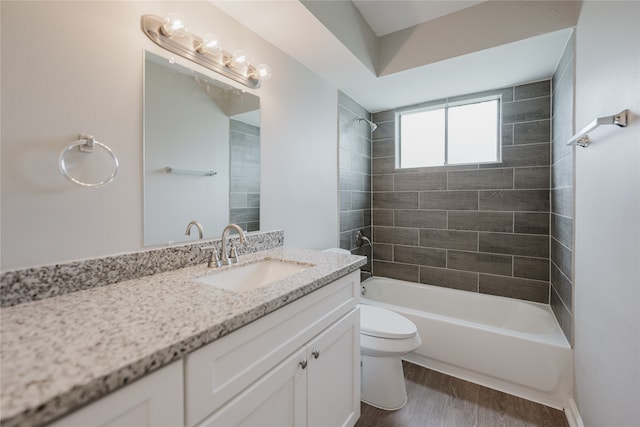 full bathroom featuring vanity, hardwood / wood-style flooring, tiled shower / bath, and toilet