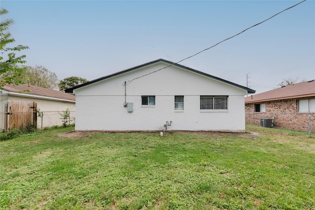 back of house with cooling unit and a yard