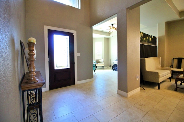 tiled foyer entrance with ceiling fan and a healthy amount of sunlight