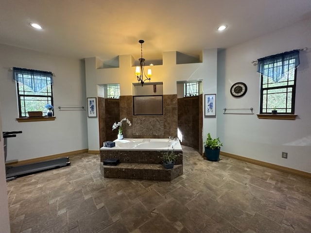 bathroom with tiled bath, plenty of natural light, and a chandelier