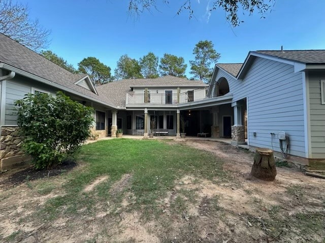 rear view of property with a balcony and a lawn