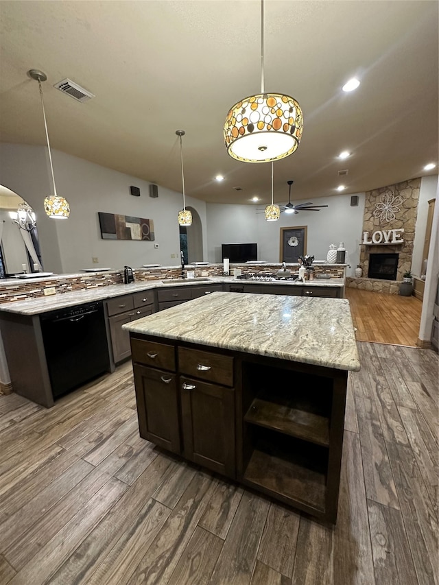 kitchen featuring ceiling fan, hardwood / wood-style flooring, a fireplace, black dishwasher, and hanging light fixtures