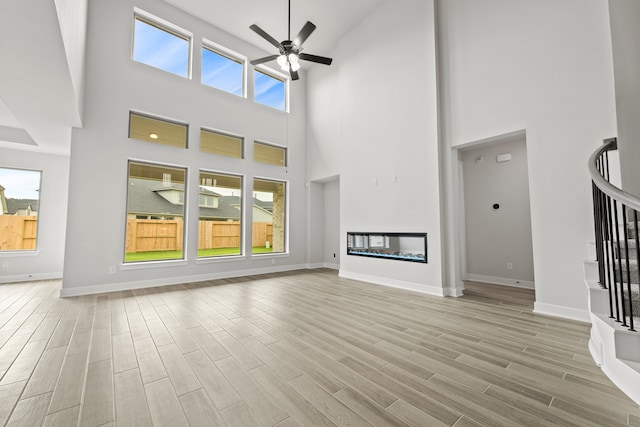 unfurnished living room with a towering ceiling, light hardwood / wood-style floors, and a wealth of natural light