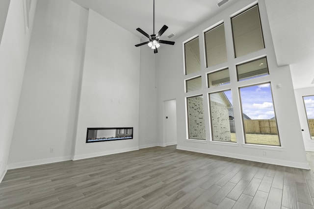 3218 Fescue Crest Ct, Brookshire, TX 77423 - unfurnished living room featuring wood finished floors, a high ceiling, ceiling fan, and a glass covered fireplace