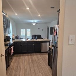 kitchen featuring light wood-type flooring, stainless steel appliances, kitchen peninsula, and ceiling fan