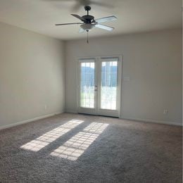 empty room featuring french doors, ceiling fan, and carpet floors