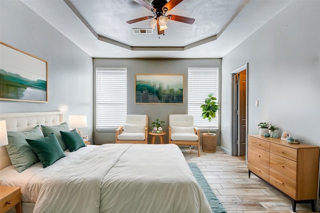 bedroom with a tray ceiling, multiple windows, and ceiling fan