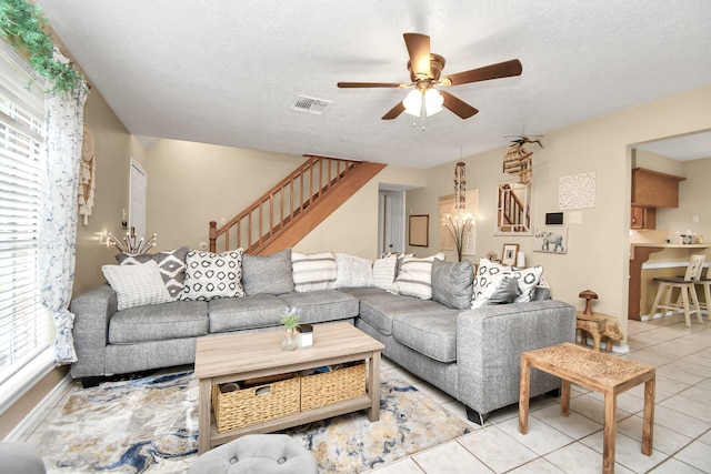 living room with ceiling fan, light tile patterned floors, and a textured ceiling