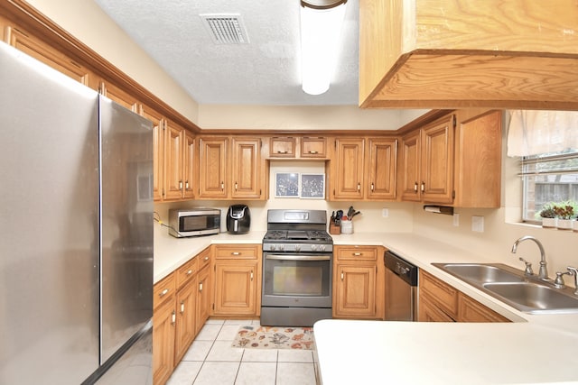 kitchen with sink, light tile patterned flooring, stainless steel appliances, and a textured ceiling