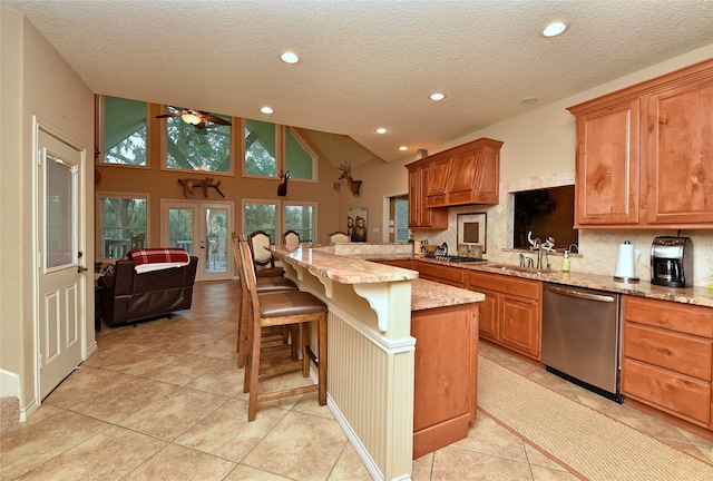 kitchen featuring appliances with stainless steel finishes, a textured ceiling, high vaulted ceiling, a breakfast bar area, and a center island