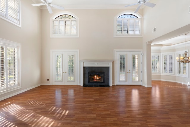 unfurnished living room with french doors, a towering ceiling, ornamental molding, and a healthy amount of sunlight