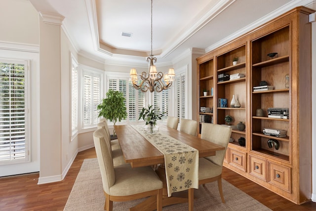 dining space with ornate columns, plenty of natural light, dark hardwood / wood-style floors, and an inviting chandelier