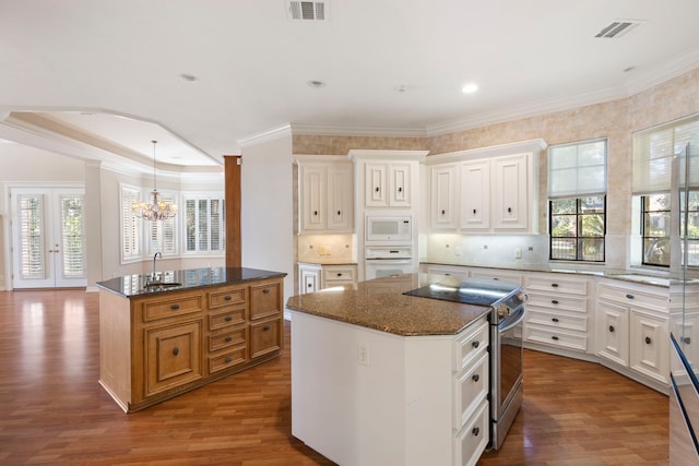 kitchen with white cabinets, white appliances, a kitchen island, and dark stone countertops