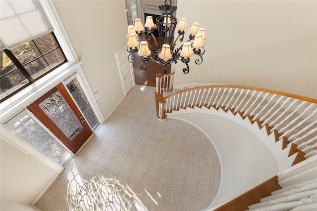 staircase with tile patterned floors, an inviting chandelier, and a high ceiling