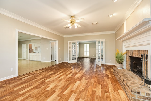 unfurnished living room featuring crown molding, french doors, ceiling fan, and a brick fireplace