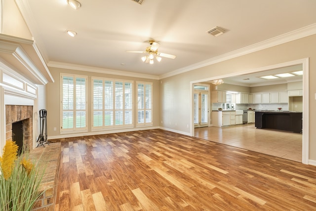 unfurnished living room featuring a brick fireplace, light hardwood / wood-style floors, ceiling fan with notable chandelier, and ornamental molding