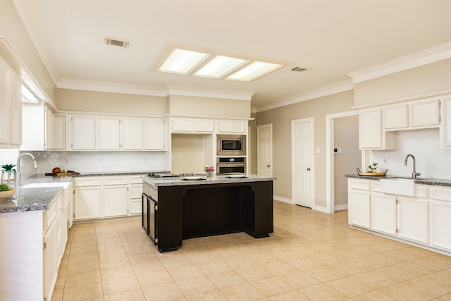 kitchen featuring dark stone countertops, light tile patterned floors, a kitchen island, white cabinetry, and stainless steel appliances