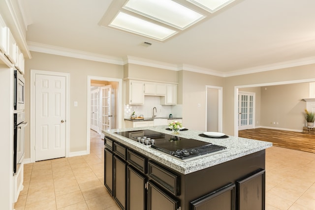 kitchen featuring light tile patterned floors, a kitchen island, white oven, black stovetop, and white cabinets