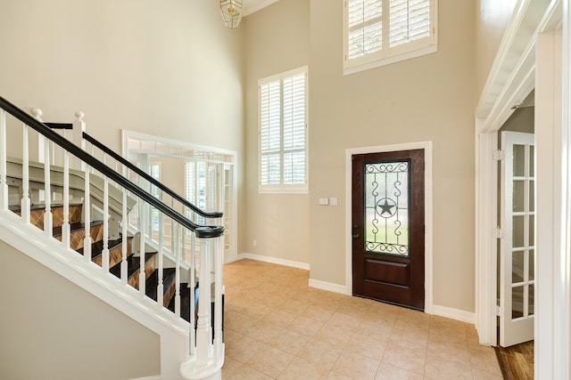 entrance foyer with light tile patterned floors and a towering ceiling