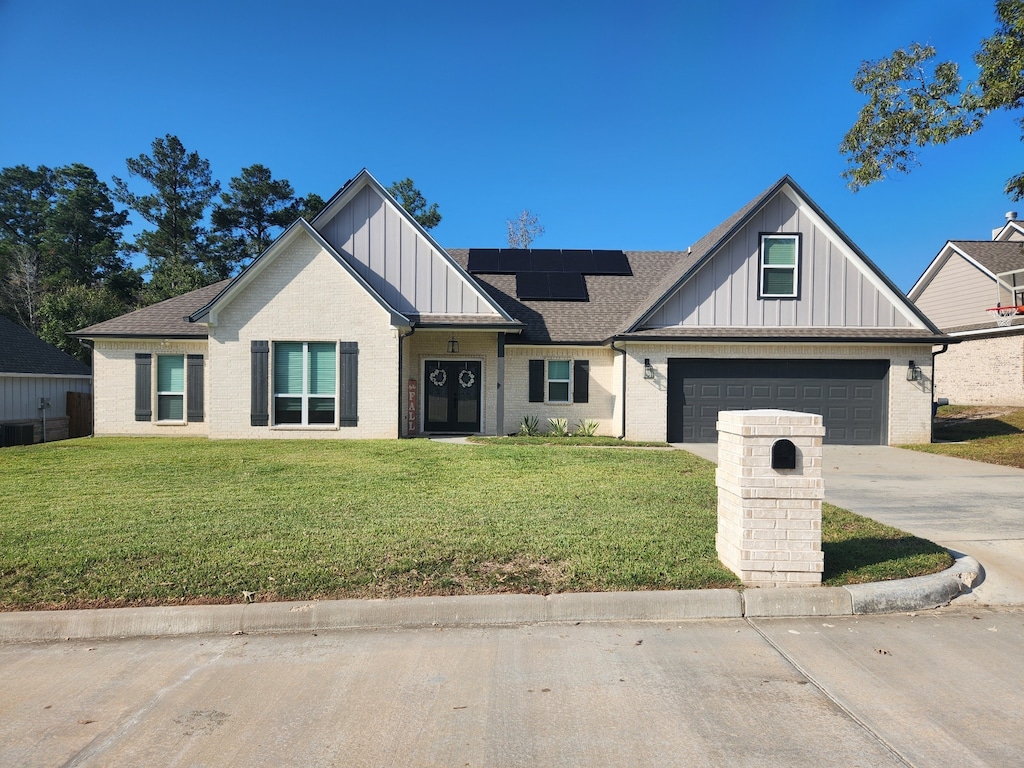 view of front facade featuring a front lawn, a garage, and solar panels