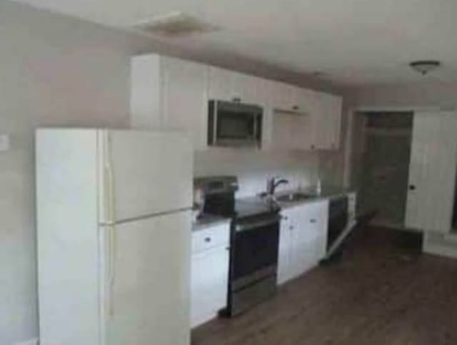 kitchen with dark hardwood / wood-style flooring, white refrigerator, sink, black range with electric stovetop, and white cabinetry