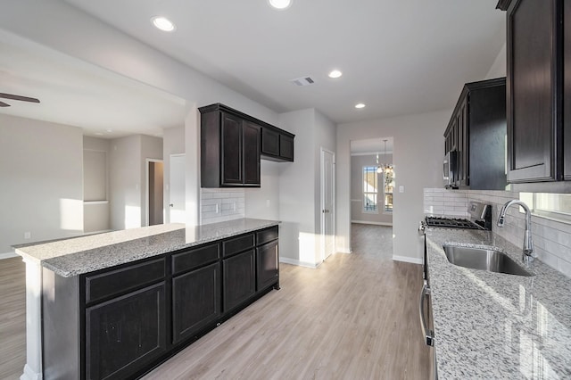 kitchen featuring light wood-type flooring, light stone countertops, sink, and backsplash