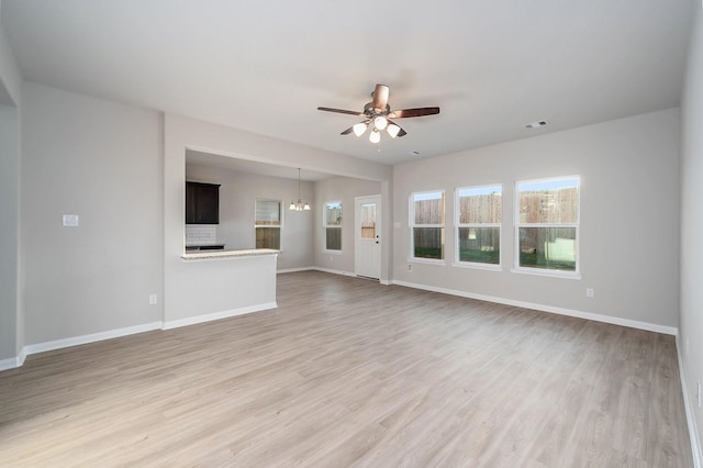 unfurnished living room featuring hardwood / wood-style flooring and ceiling fan with notable chandelier