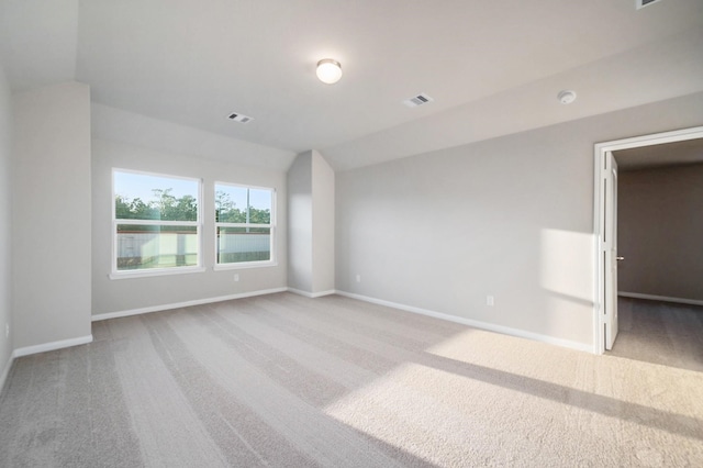 carpeted empty room featuring vaulted ceiling