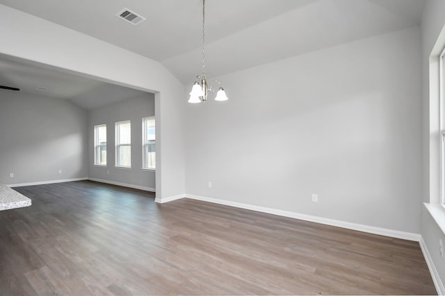 spare room with wood-type flooring, an inviting chandelier, and lofted ceiling