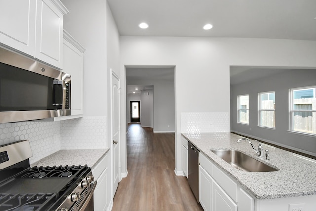 kitchen featuring stainless steel appliances, white cabinetry, sink, light stone countertops, and light hardwood / wood-style flooring