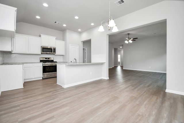 kitchen featuring white cabinetry, appliances with stainless steel finishes, light wood-type flooring, kitchen peninsula, and ceiling fan with notable chandelier