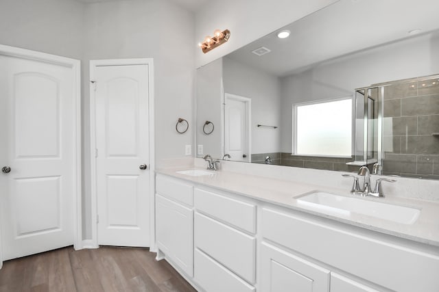 bathroom with hardwood / wood-style floors, a shower with door, and vanity