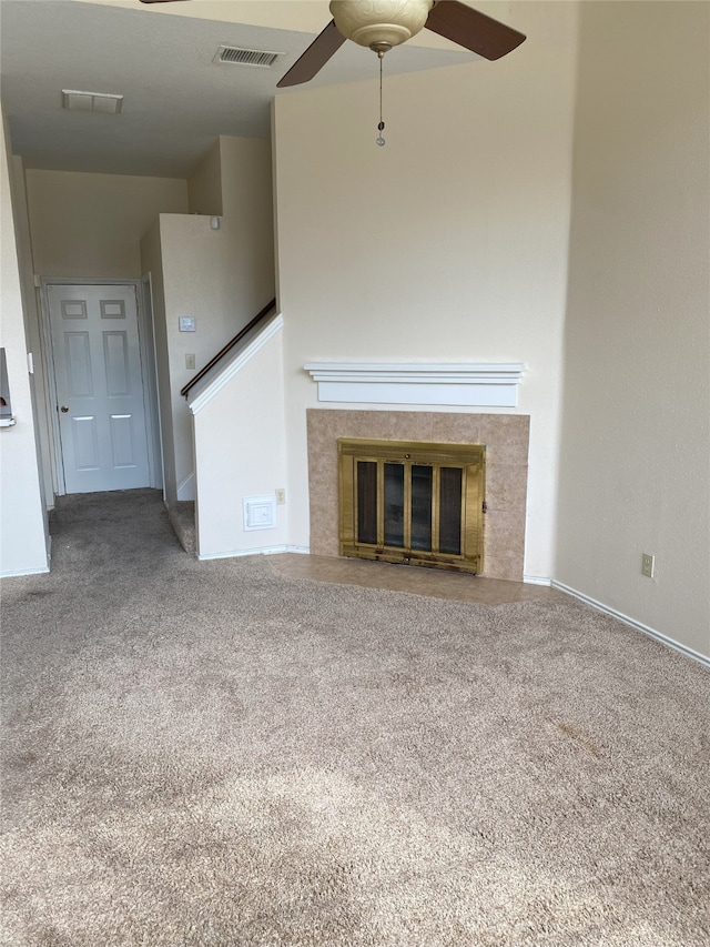 unfurnished living room with carpet, ceiling fan, and a tile fireplace