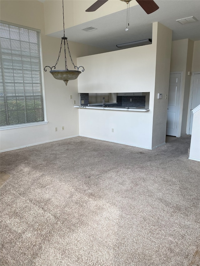 unfurnished living room with carpet floors, ceiling fan, and sink