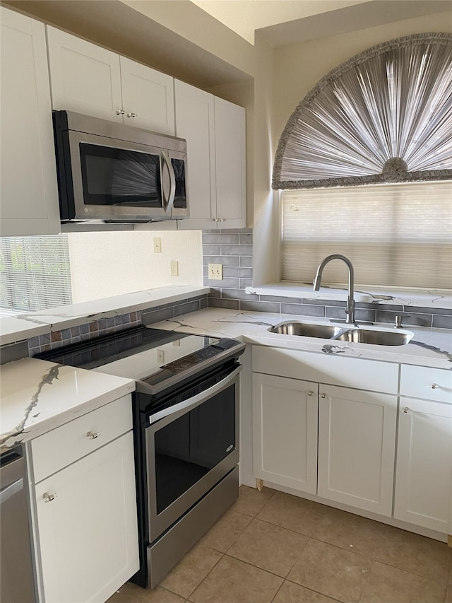 8888 Benning Dr Unit 264, Houston, TX 77031 - kitchen featuring stainless steel appliances, a sink, backsplash, white cabinetry, and light tile patterned floors
