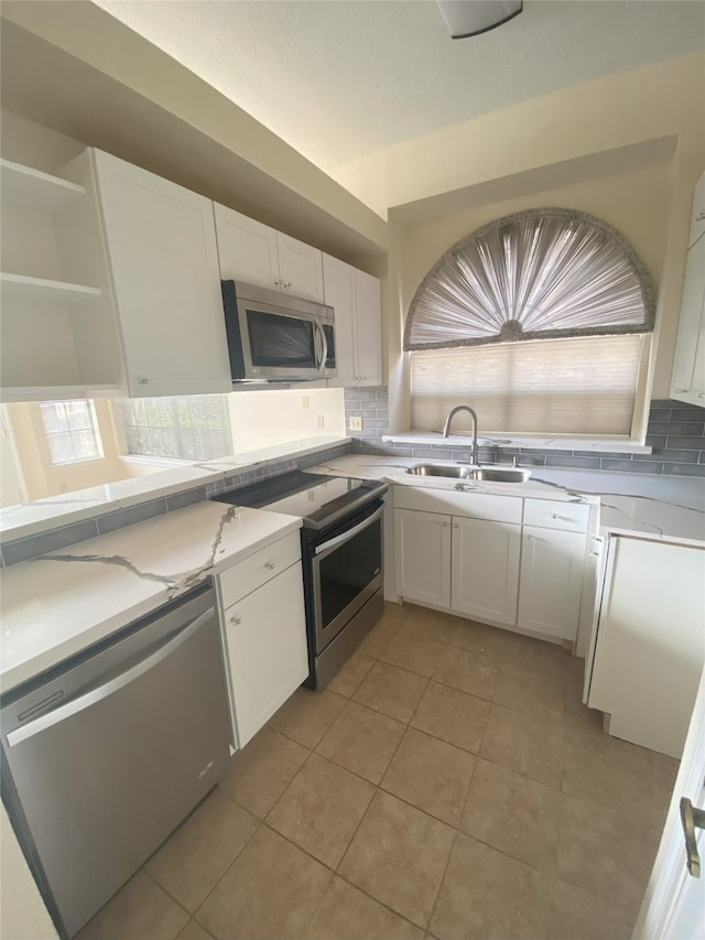 kitchen with decorative backsplash, appliances with stainless steel finishes, sink, white cabinets, and light tile patterned flooring