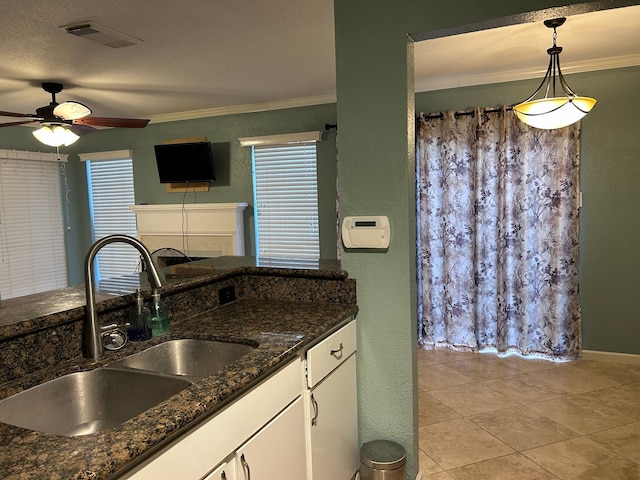 kitchen featuring dark stone counters, white cabinets, sink, hanging light fixtures, and ornamental molding