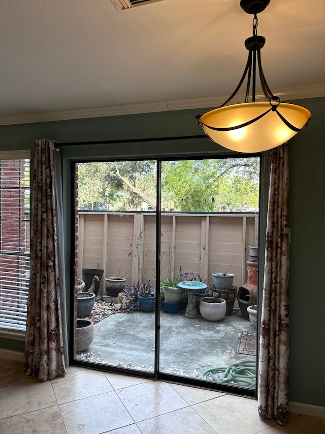 doorway to outside featuring crown molding, plenty of natural light, and light tile patterned flooring