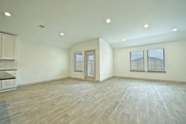 unfurnished living room featuring a wealth of natural light, light hardwood / wood-style flooring, and vaulted ceiling