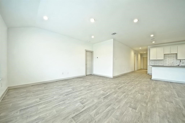 unfurnished living room with light hardwood / wood-style flooring and sink