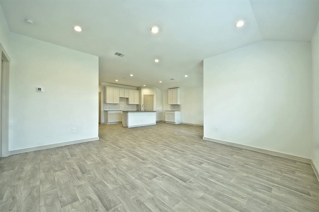 unfurnished living room featuring light wood-type flooring and vaulted ceiling