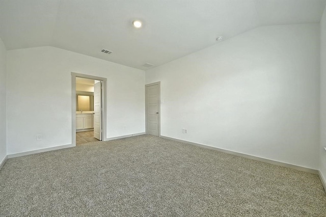 unfurnished bedroom featuring light colored carpet, ensuite bath, and lofted ceiling