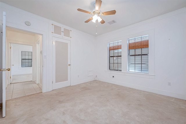 spare room featuring ceiling fan, light carpet, and crown molding