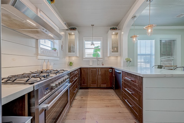 kitchen with light hardwood / wood-style floors, hanging light fixtures, extractor fan, appliances with stainless steel finishes, and white cabinetry