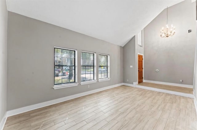 unfurnished room with high vaulted ceiling, light hardwood / wood-style flooring, and an inviting chandelier