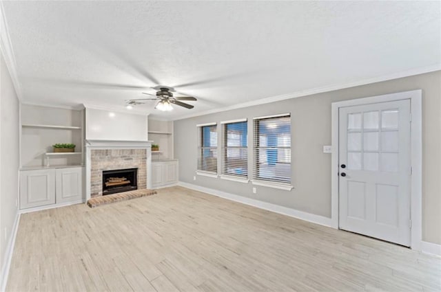 unfurnished living room featuring built in shelves, ornamental molding, a fireplace, a textured ceiling, and light hardwood / wood-style flooring