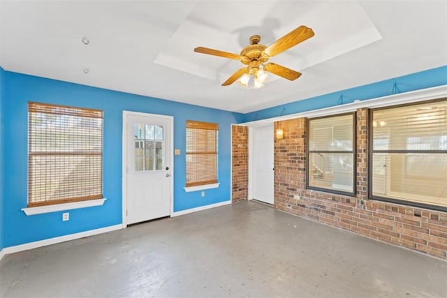 unfurnished room with ceiling fan and a raised ceiling